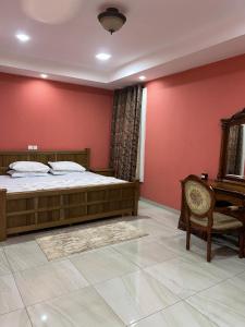 a bedroom with red walls and a bed and a chair at Villa Char in Accra