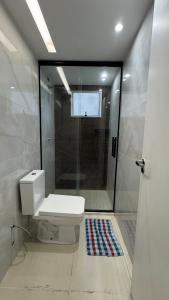 a bathroom with a toilet and a glass shower at Horto da Barra - Apartamento à Beira Mar in Barra dos Coqueiros +4 photos