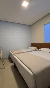 a room with two beds and a chair in it at Pousada Bella in Vitória da Conquista +5 photos