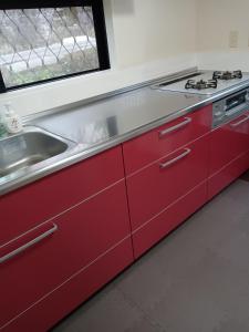 a red kitchen with a sink and a stove at guest house mami in Taketa