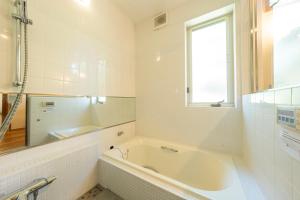 a white bathroom with a tub and a window at CALL92Chalet in Hakuba +26 photos