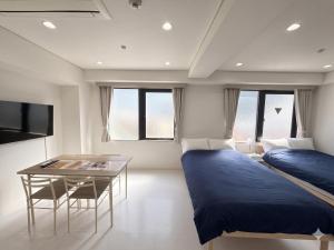 two beds and a table in a room with windows at Hotel LEAP in Osaka