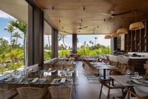 a restaurant with tables and chairs and windows at Donoma Las Terrenas Resort & Villas, Autograph Collection in Las Terrenas