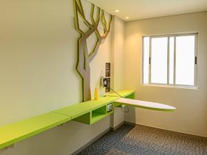 a room with a green desk and a window at ibis Styles Curitiba Centro Civico in Curitiba