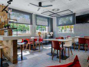 a restaurant with tables and chairs and windows at Ibis Barcelona Castelldefels in Castelldefels +116 photos