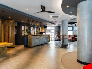a restaurant with a bar with stools and tables at Ibis Barcelona Castelldefels in Castelldefels