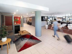 a person walking in an office lobby with a table at ibis Newcastle in Newcastle