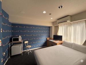 a bedroom with a bed and a desk with a computer at Hotel LEAP in Osaka