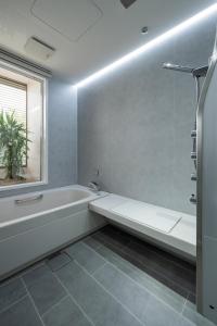 a white bathroom with a tub and a window at ホテル寺町亘hotel teramachi watari in Matsue