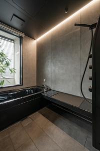 a bathroom with a bath tub and a sink at ホテル寺町亘hotel teramachi watari in Matsue