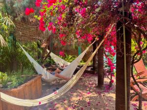 a woman laying in hammocks in a garden with flowers at Puerta Vieja Hostel in San Cristóbal de Las Casas