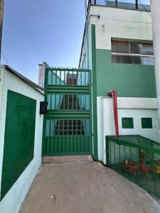 a green gate on the side of a building at Kitnets do Supermercado Simples Luxo e Deluxe! in Limeira