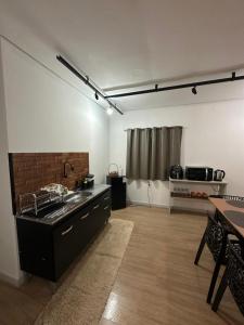 a kitchen with a sink and a table in a room at Kitnets do Supermercado Simples Luxo e Deluxe! in Limeira