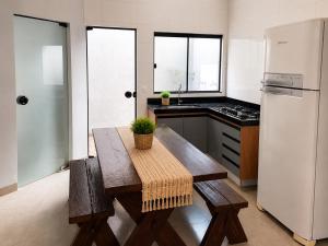a kitchen with a wooden table and a white refrigerator at Conforto e praticidade em um só local in Rio Verde
