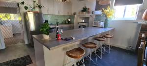a kitchen with a large counter with stools in it at Mimis Cottage in Cohuna +18 photos