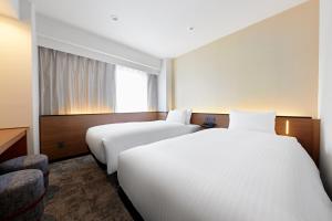 a hotel room with two beds and a window at Sotetsu Grand Fresa Osaka-Namba in Osaka