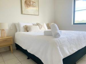 a bedroom with a bed with white sheets and pillows at Beach Days, Ocean Rooftop & Spa - Sleeps 8 in Marcoola