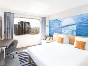 a hotel room with a bed and a desk and a window at Novotel Paris Centre Tour Eiffel in Paris