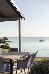a wooden table and chairs with a view of the ocean at Circular Bay in Awaroa +9 photos