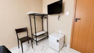 a room with a television and a chair and a refrigerator at Made Hotel in São Luís
