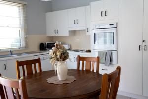 a kitchen with a wooden table with a vase of flowers on it at Heritage On Horseshoe Guest House in South West Rocks +52 photos