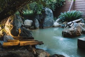 a pond with a bench in the water with rocks at Koran no Yu Kinkouro in Ibusuki +60 photos