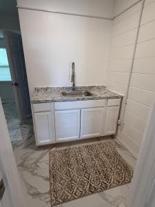 a white bathroom with a sink and a rug at Studio sunshine in St. Petersburg