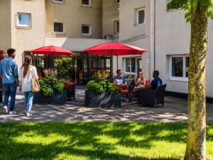 a group of people sitting in chairs under red umbrellas at Ibis Orly Chevilly Tram 7 in Chevilly-Larue