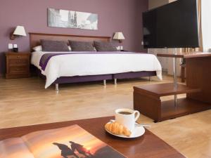 a bedroom with a bed with a cup of coffee and a plate of food at Mercure Alameda Quito in Quito +74 photos