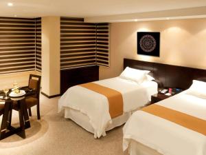 a hotel room with two beds and a table at Mercure Alameda Quito in Quito