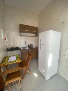 a kitchen with a table and a white refrigerator at Lindo APTO bem localizado em Sinop! in Sinop