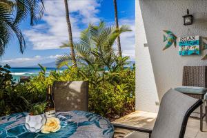 a table and chairs on a patio with a view of the ocean at Hale Mahina A102 in Kahana