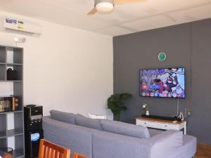 a living room with a blue couch and a tv on a wall at Villa Flora Bella Yellow Bell in Dauis