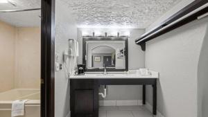 a bathroom with a sink and a mirror and a tub at Super 8 by Wyndham Norman West OK in Norman