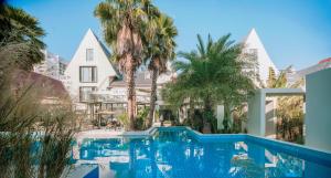 a swimming pool in front of a building with palm trees at Silver Beach Yuese Hostel in Beihai