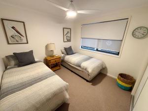 a bedroom with two beds and a window with a clock at Jubilee Apartment 05 - Bring your own linen in South West Rocks +12 photos