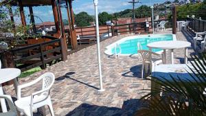 a patio with tables and chairs and a swimming pool at Pousada Campo Alegre Eireli in Itatiaia