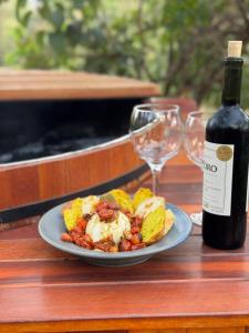 a plate of food with a bottle of wine and glasses at Chales Estrela Veadeiros Com Ofurô in Alto Paraíso de Goiás