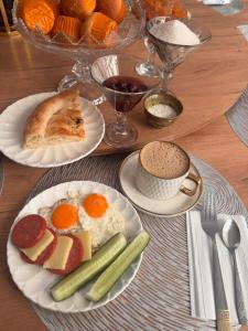 a table with plates of breakfast food and a cup of coffee at Friendly House in Bokonbayevo