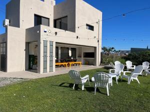 a group of chairs sitting on the grass in front of a house at Las moras quinta in San Nicolás de los Arroyos