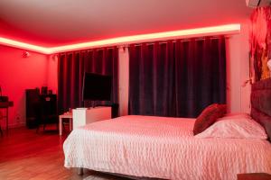 a bedroom with red walls and a bed and a television at Suite Touraco, clim, balneo, terrasse - Parc des Oiseaux in Villars-les-Dombes
