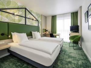 a hotel room with two beds and a green wall at Mercure Hotel Hannover Mitte in Hannover +247 photos