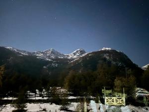 a view of snow covered mountains under a night sky at Cabaña Laguna Huemul in Pinto