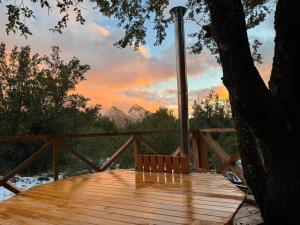 a wooden deck with a table and a tree at Cabaña Laguna Huemul in Pinto