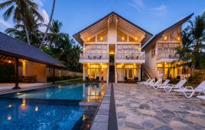 a villa with a swimming pool in front of a building at The Oceans Edge in Dodanduwa