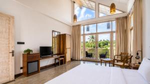 a bedroom with a bed and a large window at The Oceans Edge in Dodanduwa