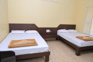 two beds in a small room with towels on them at Horanadu Sanman residency in Kalasa