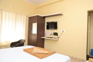 a bedroom with a bed and a tv on the wall at Horanadu Sanman residency in Kalasa