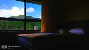 a bed with a window with a view of a mountain at Horanadu Sanman residency in Kalasa