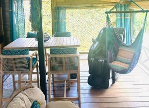 a porch with a hammock and a table and chairs at Escale verdoyante in Petit-Bourg